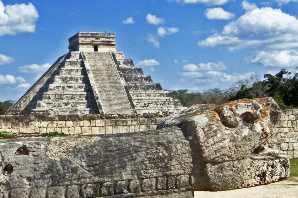 The stepped pyramid El Castillo at Chichen Itza, Yucatán, Mexico, seen from the north, with its serpent-head sculptures at the base of the northern staircase visible in the foreground.