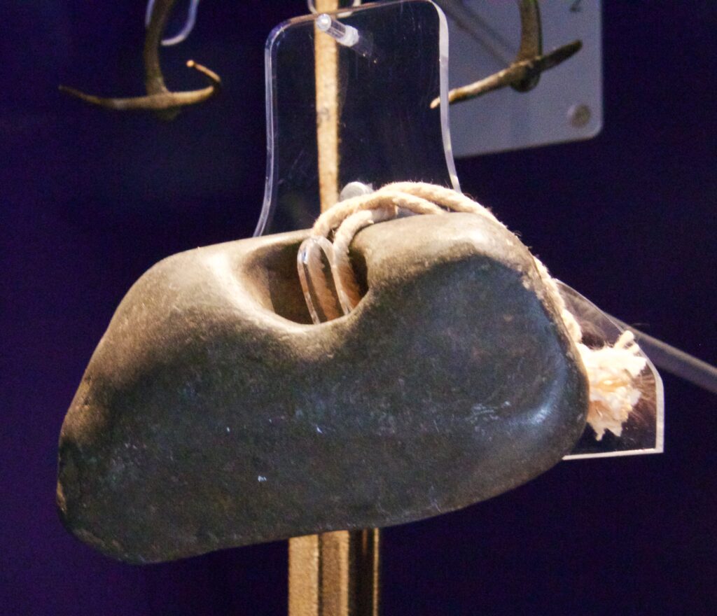 Small perforated flint stone, known as an adder stone, displayed at Clitheroe Castle Museum.