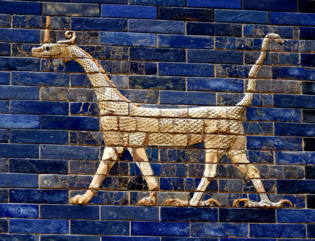 A horned, scaled dragon in blue and gold glazed brick relief, with a snake's head, lion's forelegs, and a bird's clawed hind legs.